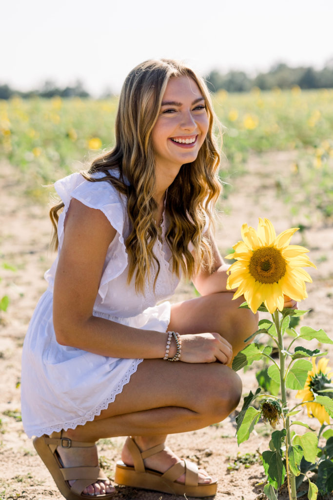 girl laughing while smelling a sunflower
