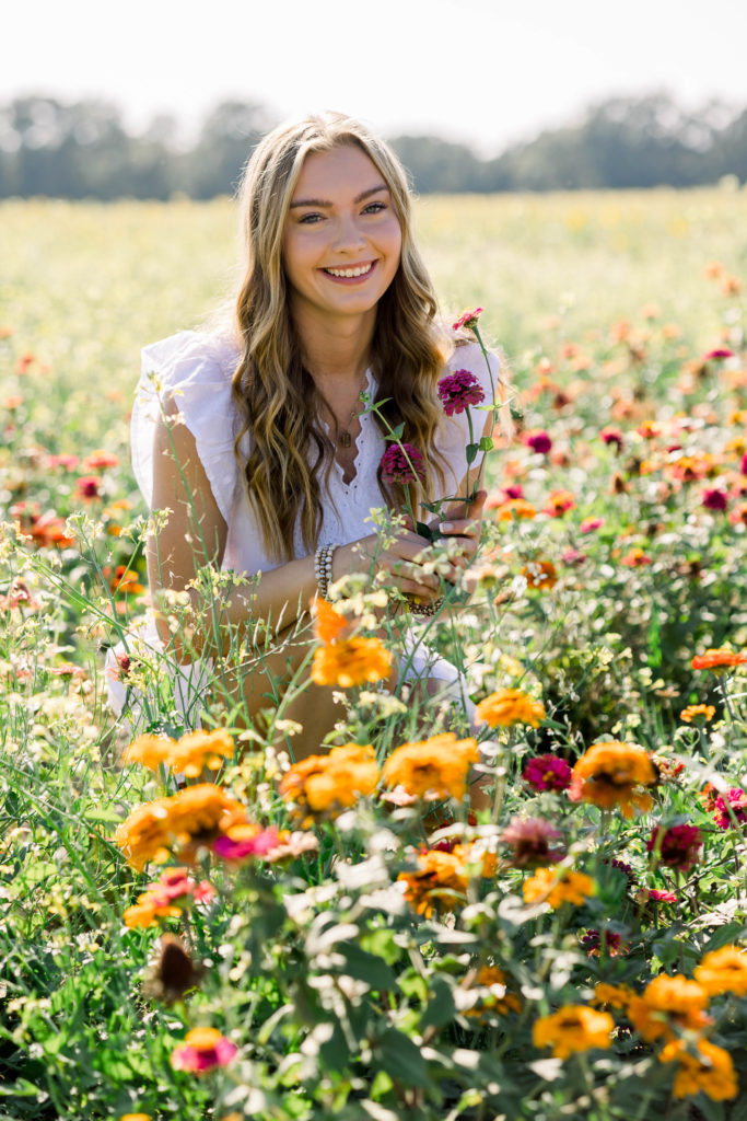 Senior smiling in a field of zinnia wildflowers