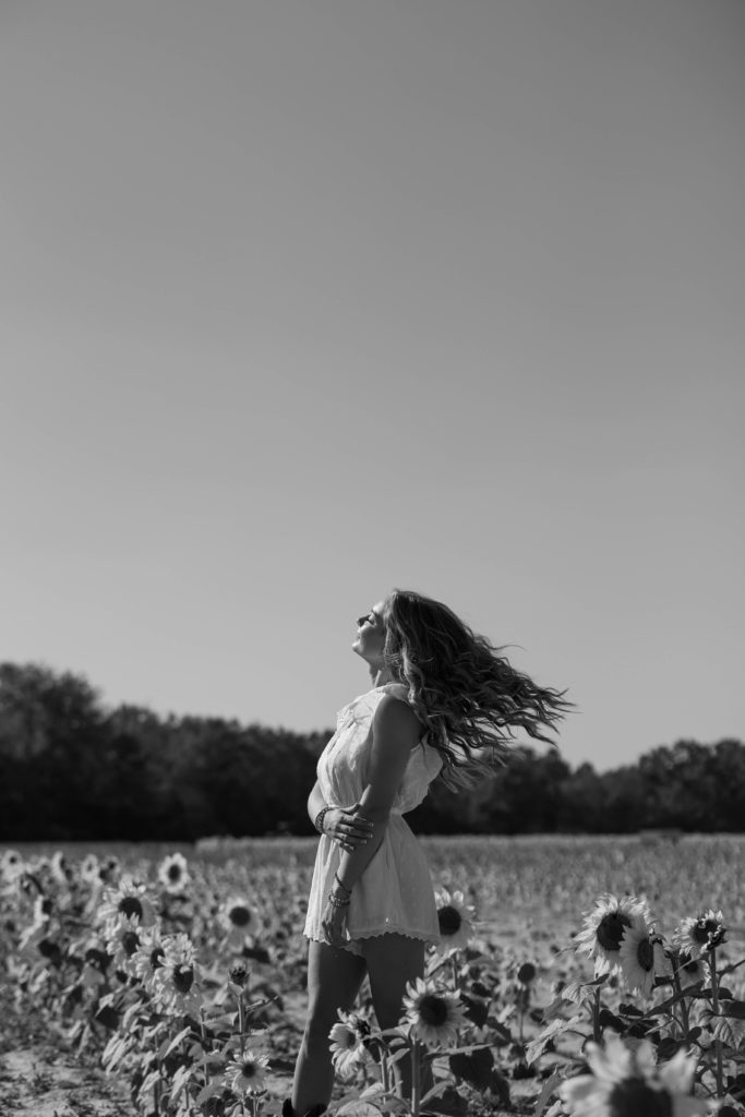 black and white image of a girl twirling in sunflowers