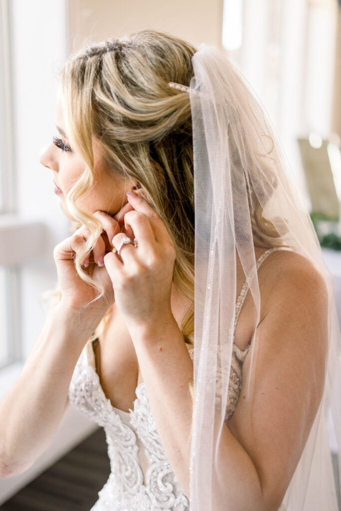 Bride putting on earring at Scenic Hills Country Club in Pensacola