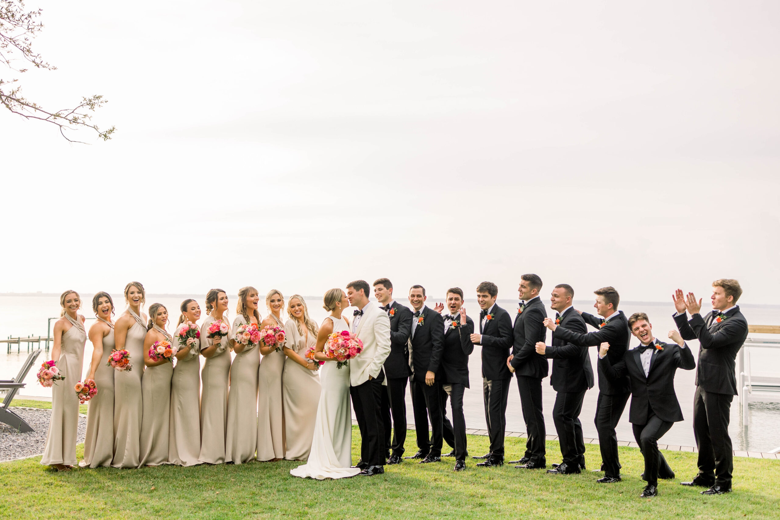 Bridal Party posing on a wedding day while bride and groom kiss