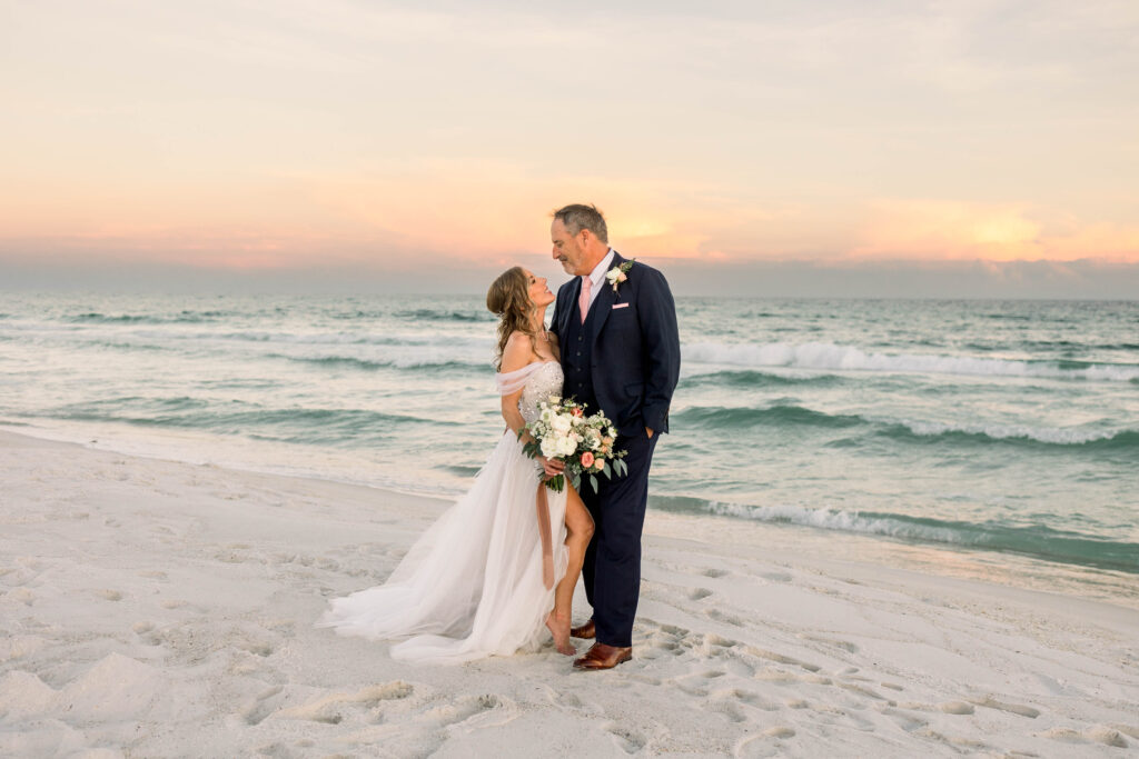 Couple posing on beach at sunset in their wedding dress and suit