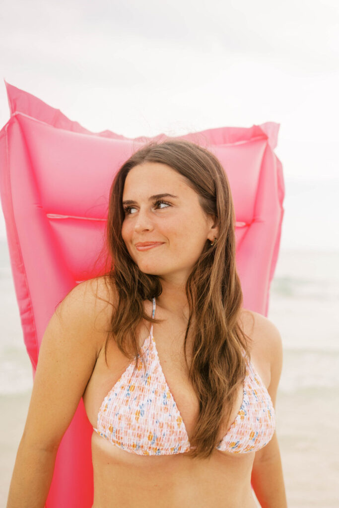 Girl with a pink floatie on the beach