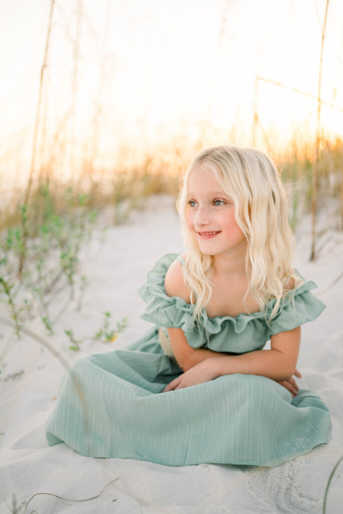 Daughter posing on the dunes of the beach for a family photo looking at the water