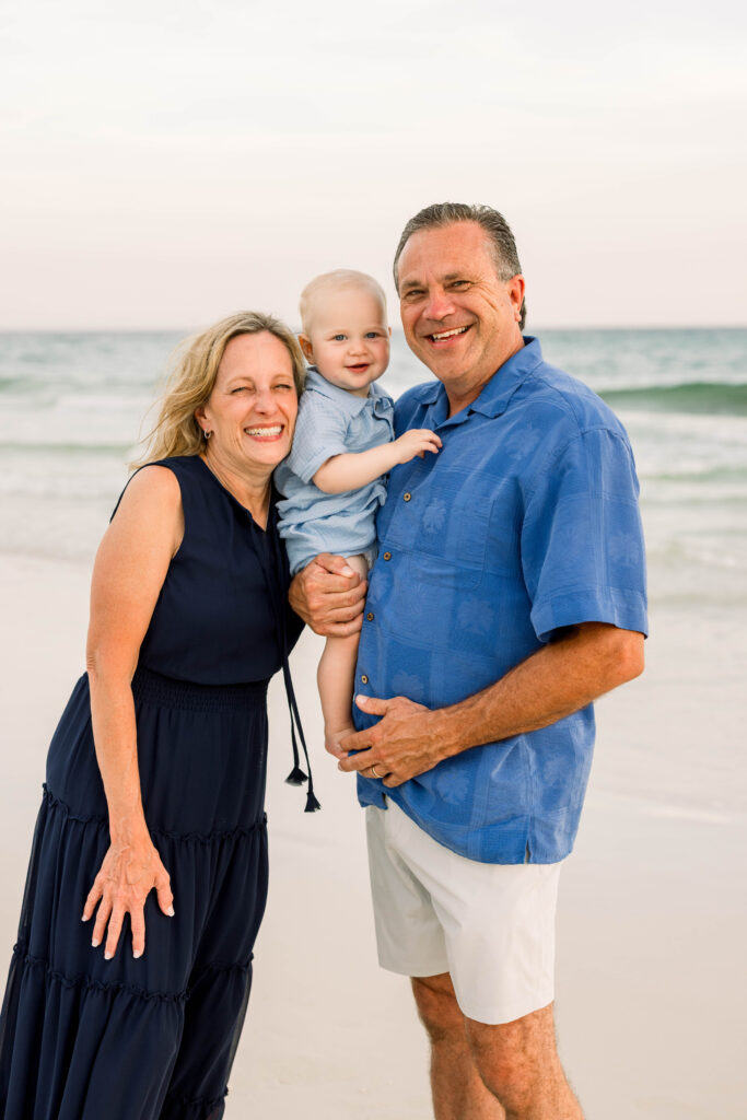 Grandparents holding their smiling baby on Rosemary Beach