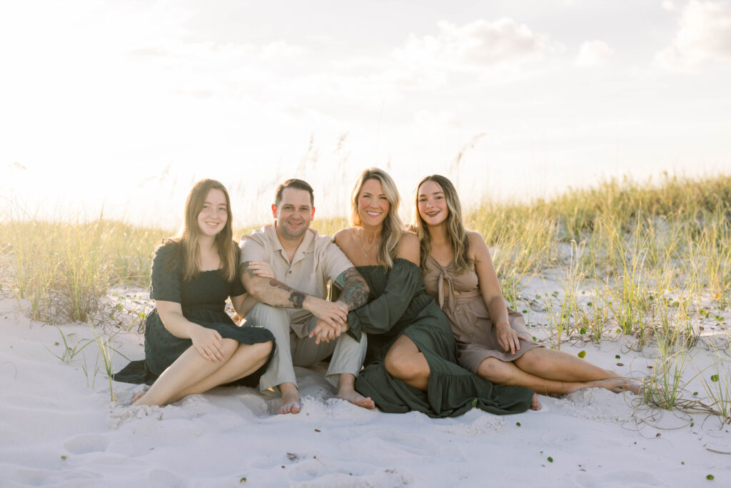 A family of four sitting by the dunes at fort pickens in pensacola beach