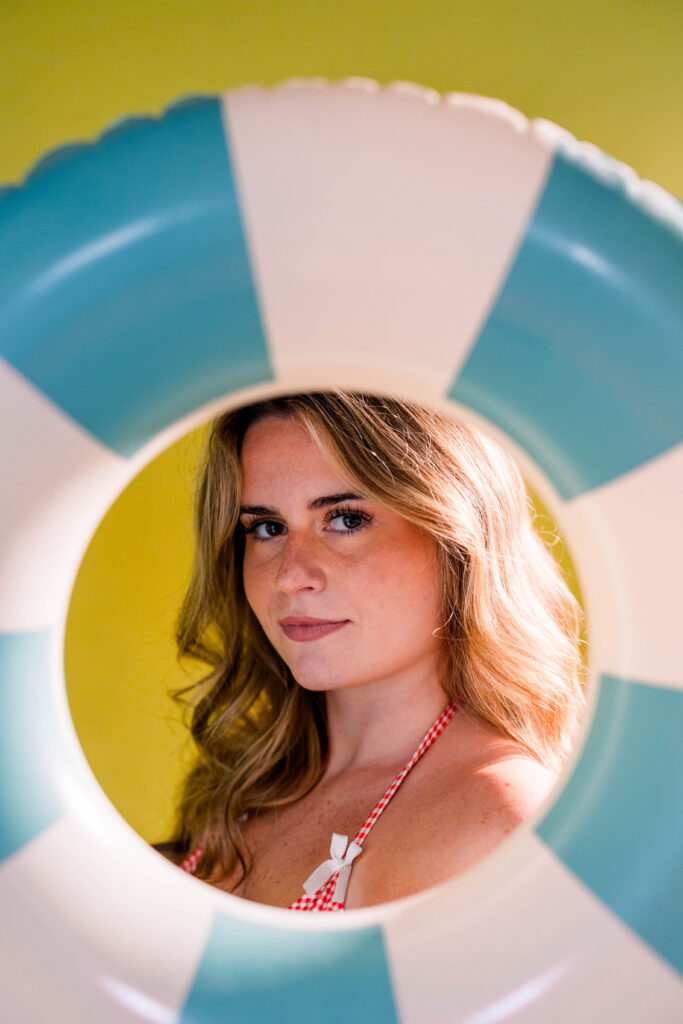 A girl posing for a summer photoshoot with her face in a floatie